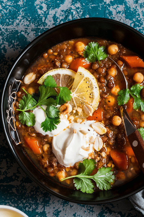 Spicy Moroccan Sweet Potato Soup is a healthy and flavorful vegan sweet potato soup loaded with plant-based protein lentils and vegetables. One of our favorite clean eating crockpot recipes for dinner! Harissa paste gives this detox soup an authentic Moroccan flavor! #soup #vegan #vegetarian #glutenfree #dairyfree #healthy #sweetpotato #cilantro #chickpeas #harissa #moroccan #souprecipes #detoxsoup