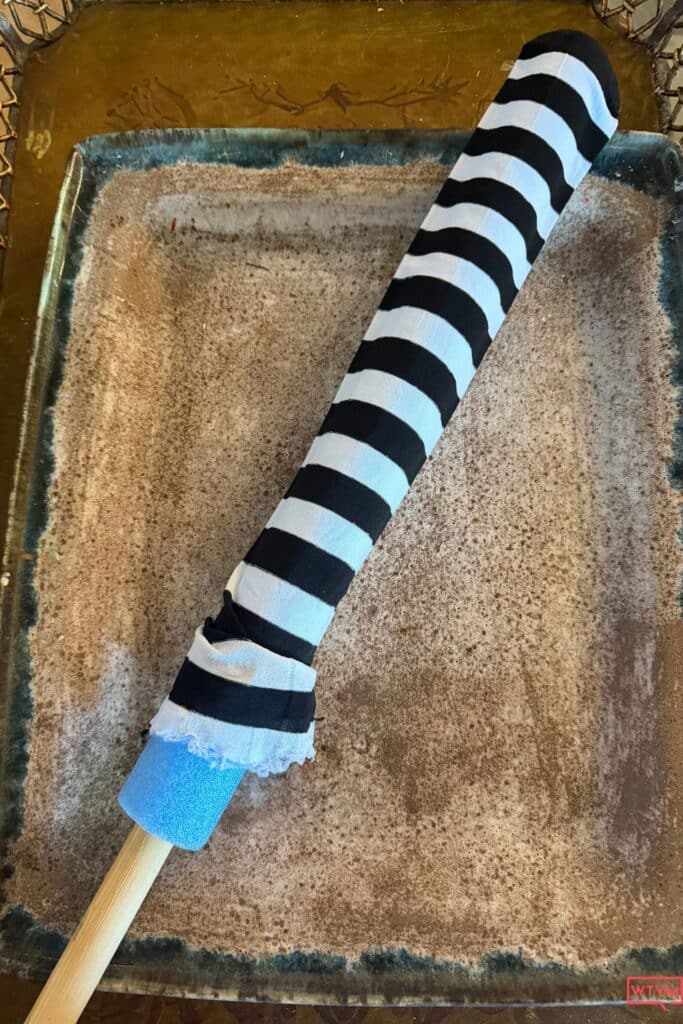 Striped tights pulled over a pool noodle with a wooden dowel inside for DIY witch legs